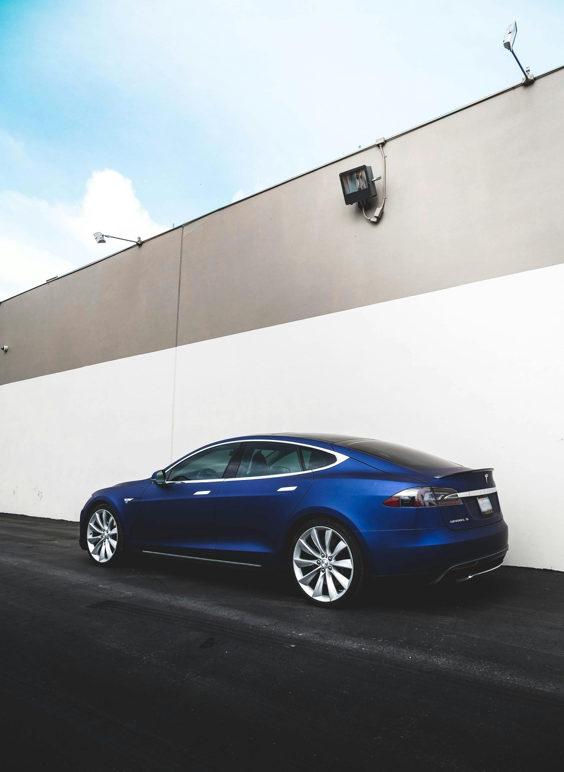 A stylish blue sedan parked by a contemporary urban wall, showcasing modern elegance.
